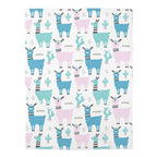 A square fabric item, likely a blanket or towel, featuring a repeating pattern of cartoon llamas and cacti in shades of blue, pink, and teal on a white background.